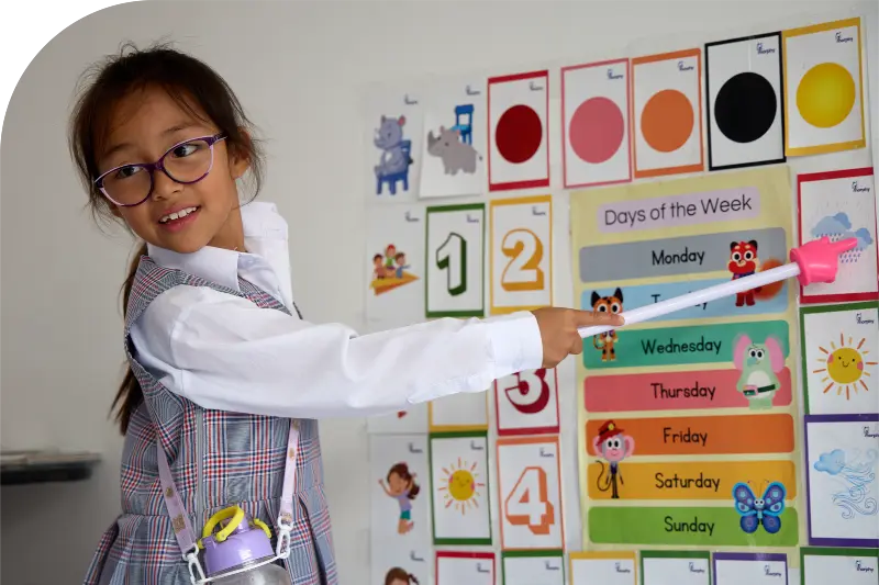 niña de 6 años, señalando en un tablero unas nubes para que sus compañeros digan el nombre en ingles. Morphy es ingles.