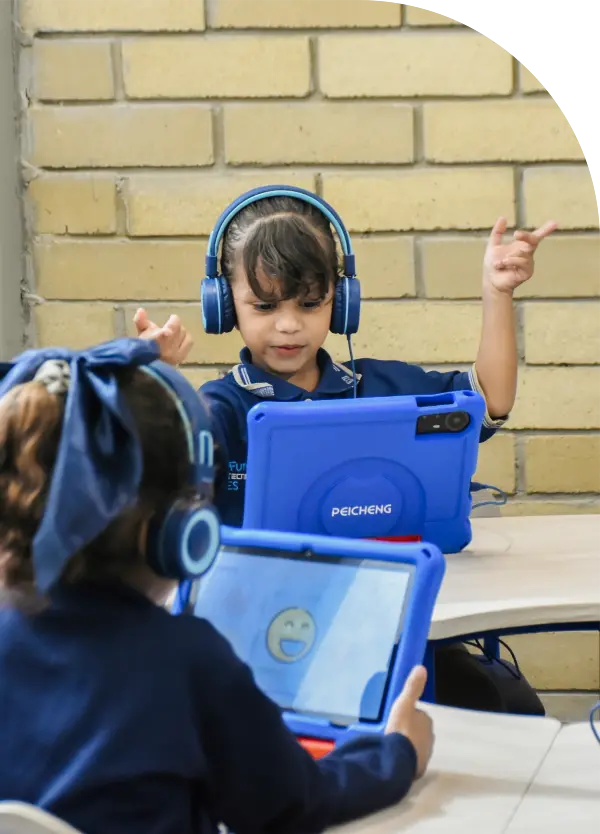 Foto de una niña de 4 años, frente a una table, levantando los brazos en señal de divertirse mientras aprende ingles con Morphy. 