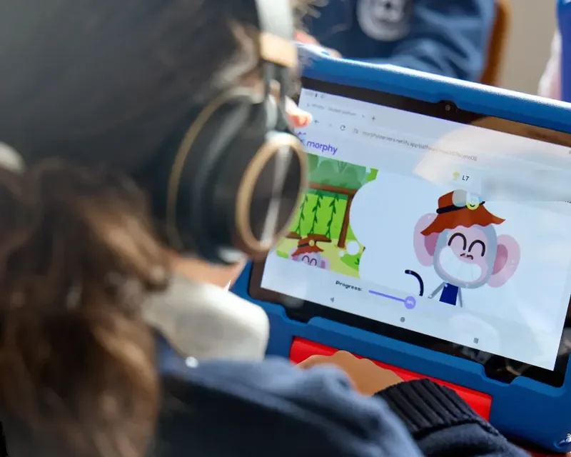 Niña con audífonos haciendo una lección de Morphy en su tablet