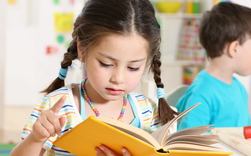 Niña siguiendo con el dedo las palabras de un libro