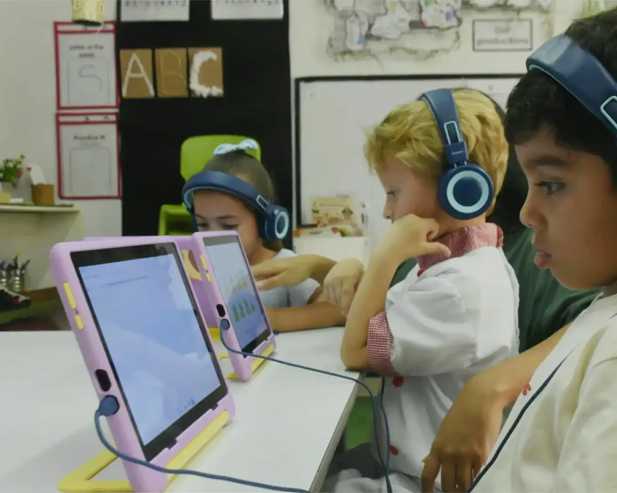 Niños con audífonos haciendo una lección de Morphy en sus tablets